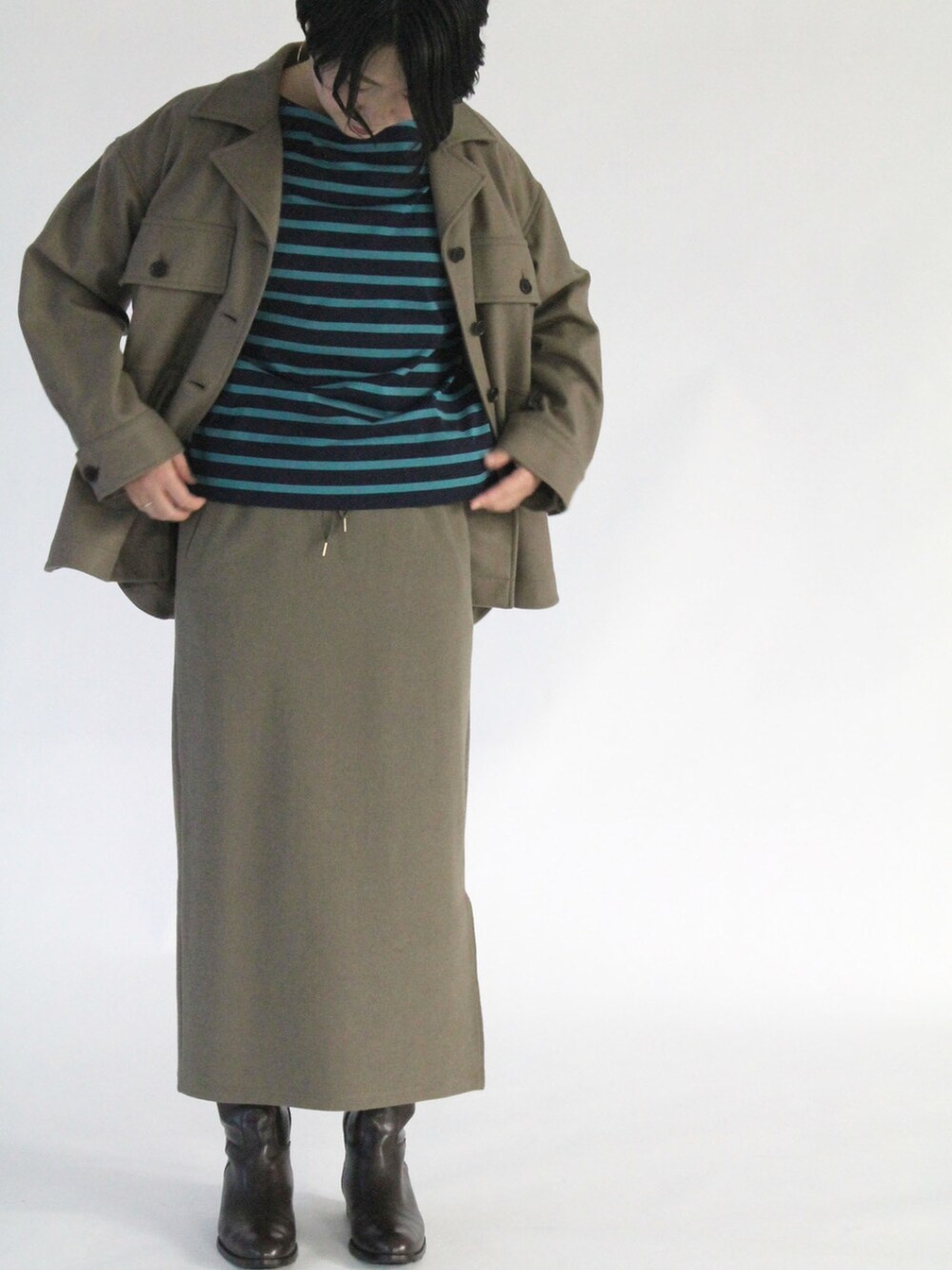 ブルー系のTシャツ/カットソー、ブラウン系のダウンジャケット/コート、グリーン系のスカートを着用したレディースの秋コーディネートの4枚目の写真