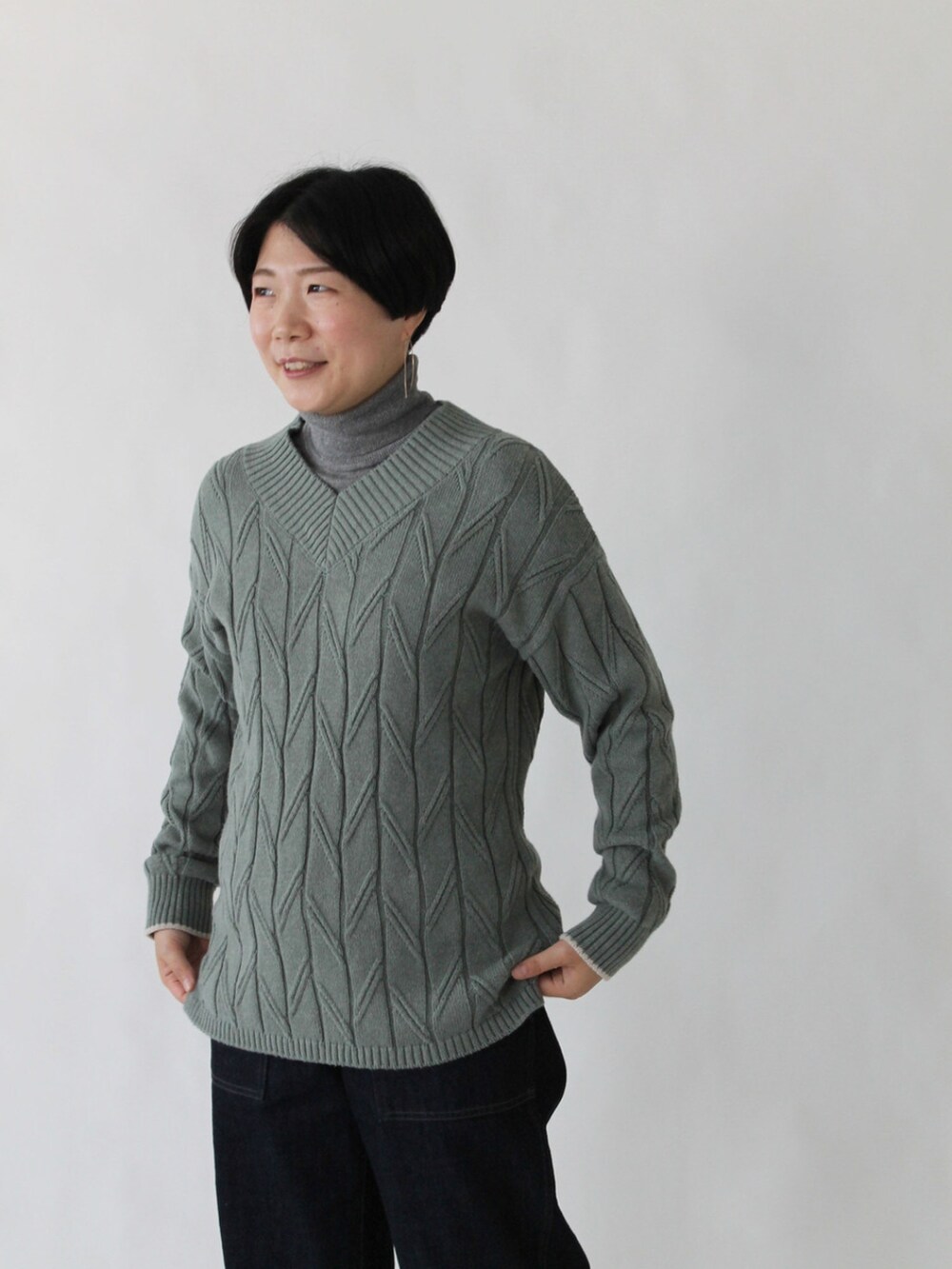 グリーン系のニット/セーター、ブルー系のデニムパンツ、ベージュ系のその他アウターを着用したレディースの秋コーディネートの4枚目の写真