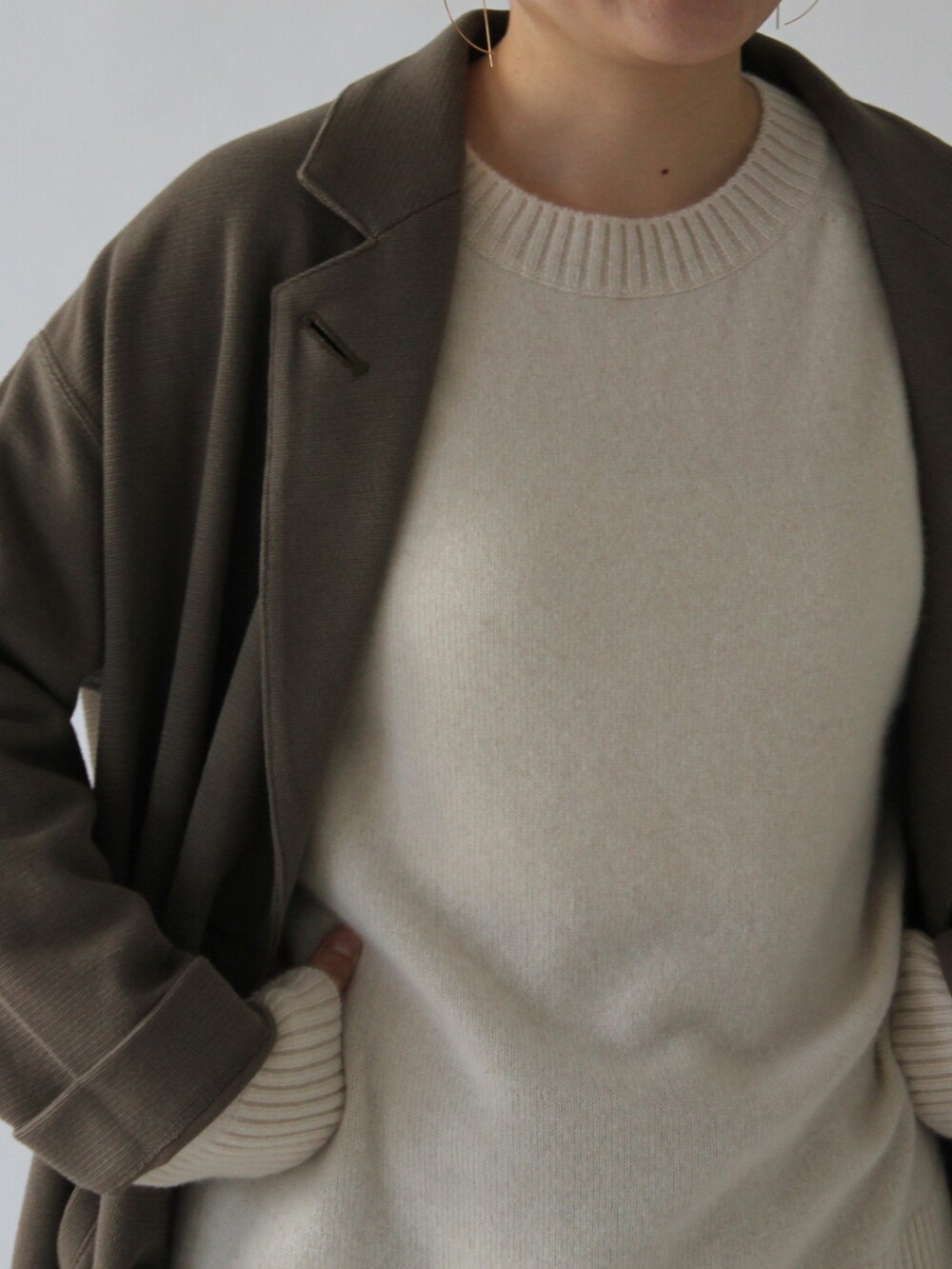 ブラウン系のスカート、グリーン系のチェスターコート、ベージュ系のニット/セーターを着用したレディースの冬コーディネートの2枚目の写真