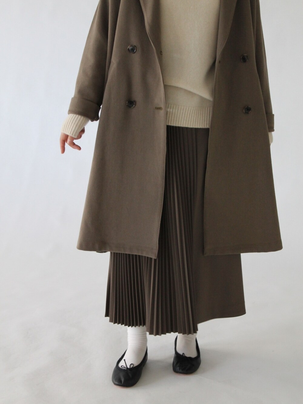 ブラウン系のスカート、グリーン系のチェスターコート、ベージュ系のニット/セーターを着用したレディースの冬コーディネートの3枚目の写真