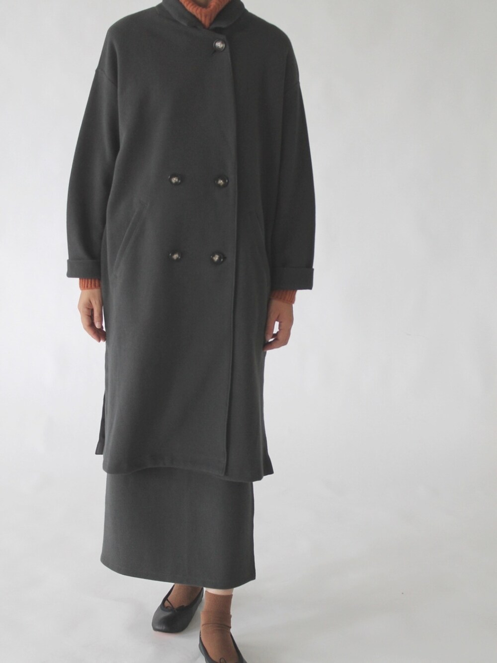 オレンジ系のニット/セーター、グレー系のチェスターコート、グレー系のスカートを着用したレディースの冬コーディネートの4枚目の写真