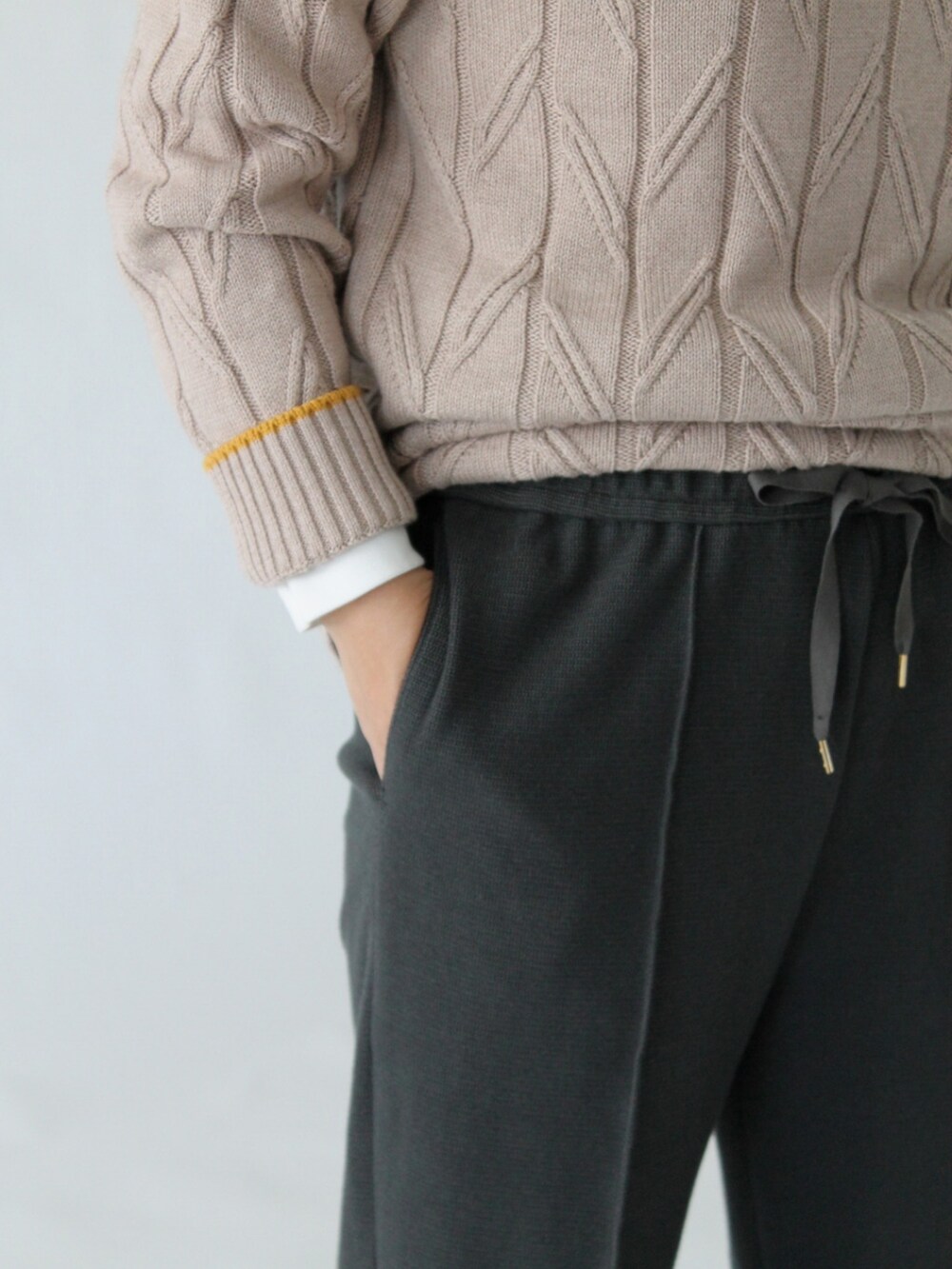 グレー系のパンツ、ベージュ系のニット/セーター、ホワイト系のトップスを着用したレディースの冬コーディネートの5枚目の写真