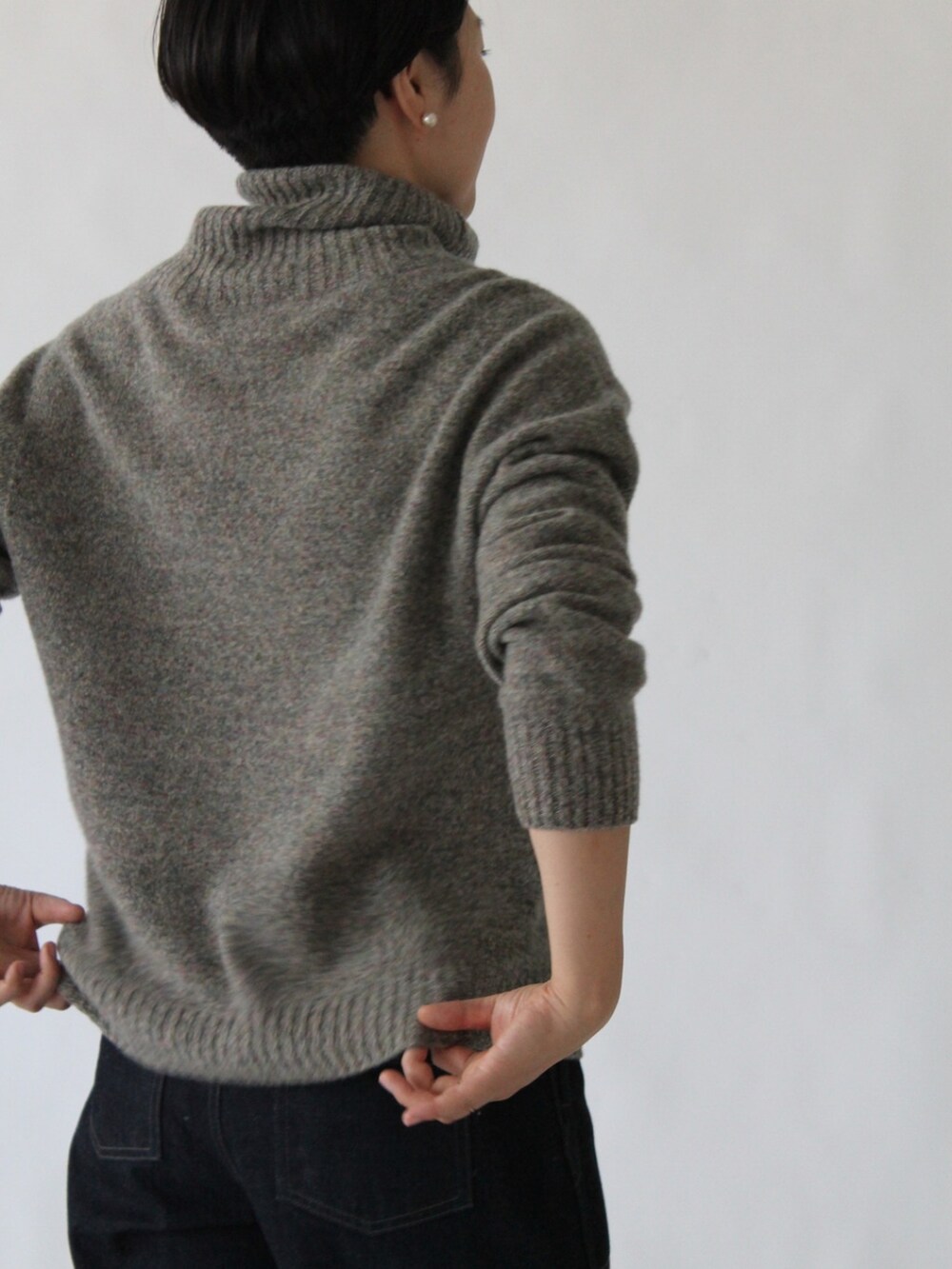 グレー系のニット/セーター、ブルー系のデニムパンツを着用したレディースの冬コーディネートの2枚目の写真