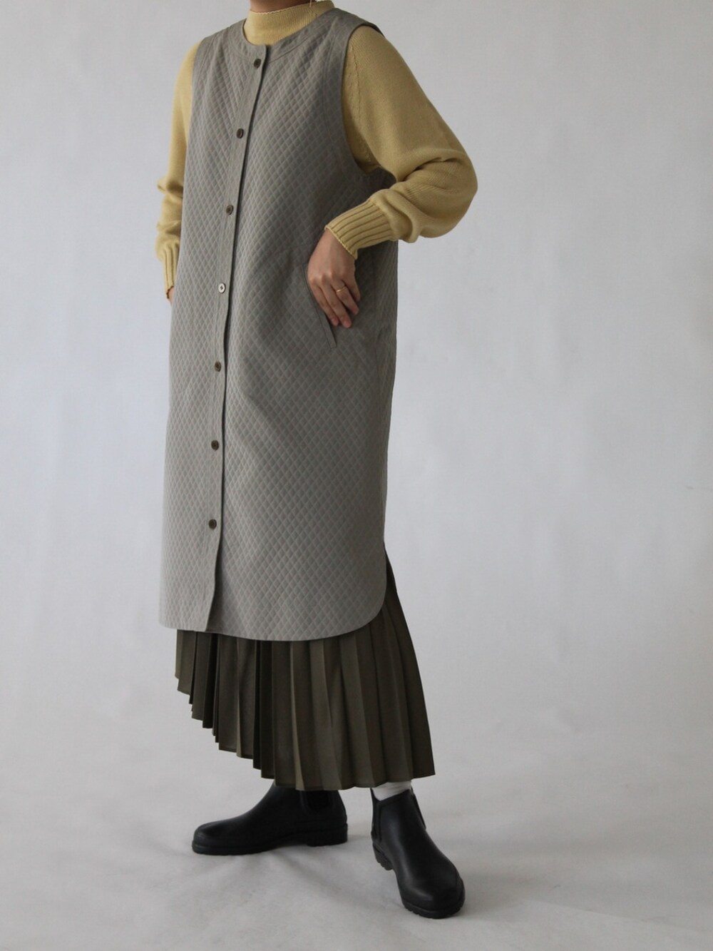 グリーン系のスカート、グリーン系のワンピース、イエロー系のニット/セーターを着用したレディースの冬コーディネートの3枚目の写真