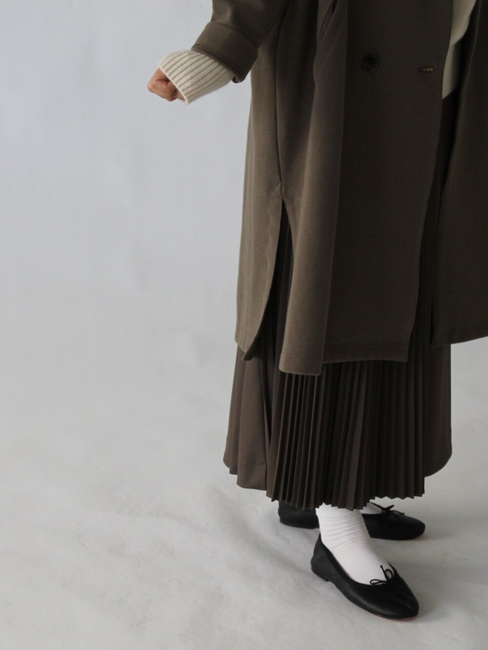 ブラウン系のスカート、グリーン系のチェスターコート、ベージュ系のニット/セーターを着用したレディースの冬コーディネートの4枚目の写真