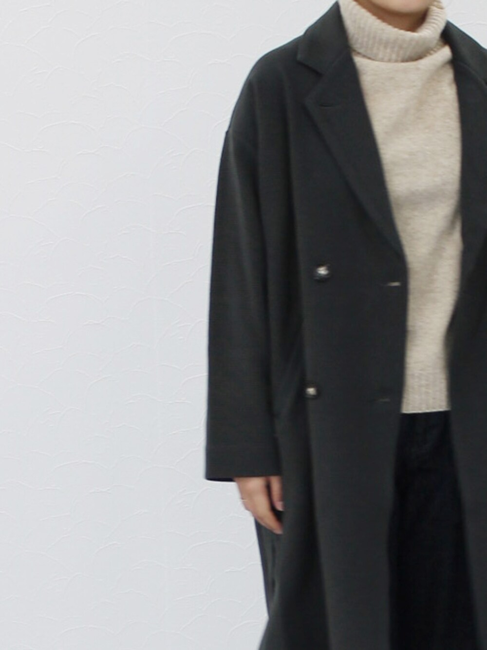 グレー系のチェスターコート、ベージュ系のニット/セーター、ブルー系のデニムパンツを着用したレディースの秋コーディネートの4枚目の写真