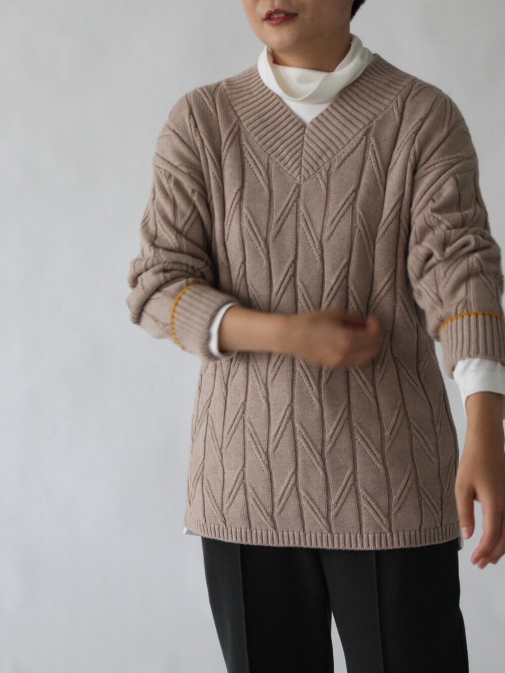 グレー系のパンツ、ベージュ系のニット/セーター、ホワイト系のトップスを着用したレディースの冬コーディネートの2枚目の写真