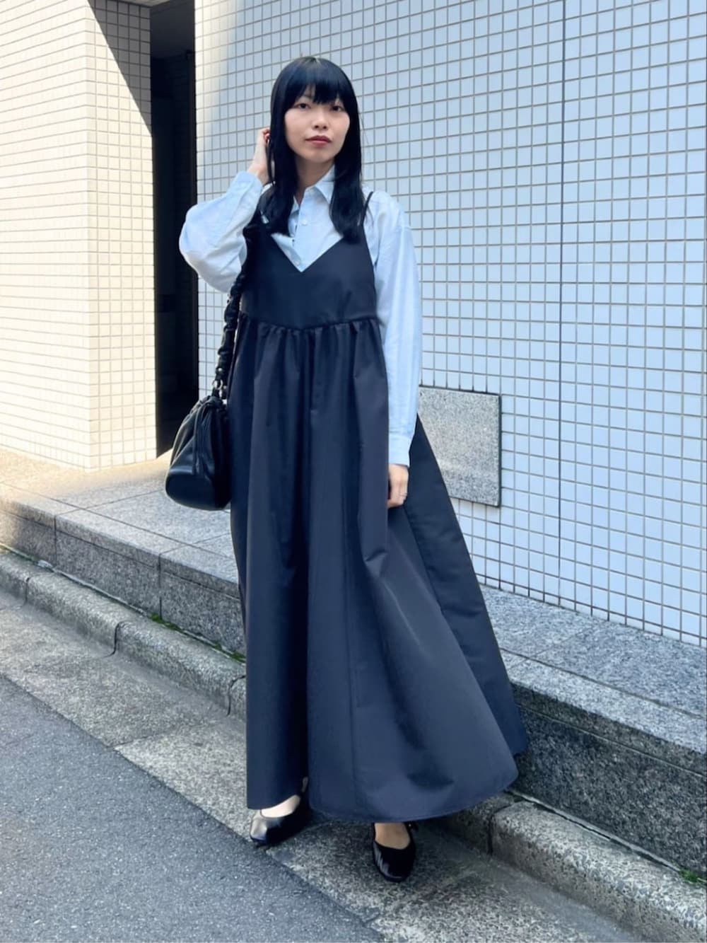 ブラック系のワンピース、ブルー系のシャツ/ブラウス、ブラック系のパンプスを着用したレディースの春コーディネートの2枚目の写真