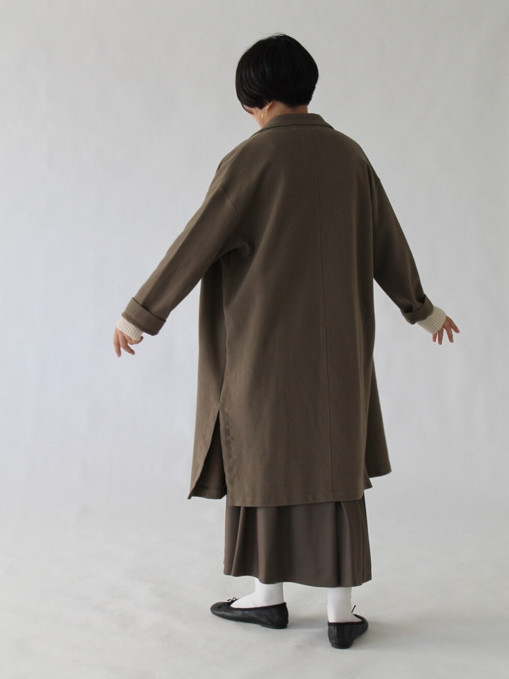 ブラウン系のスカート、グリーン系のチェスターコート、ベージュ系のニット/セーターを着用したレディースの冬コーディネートの5枚目の写真