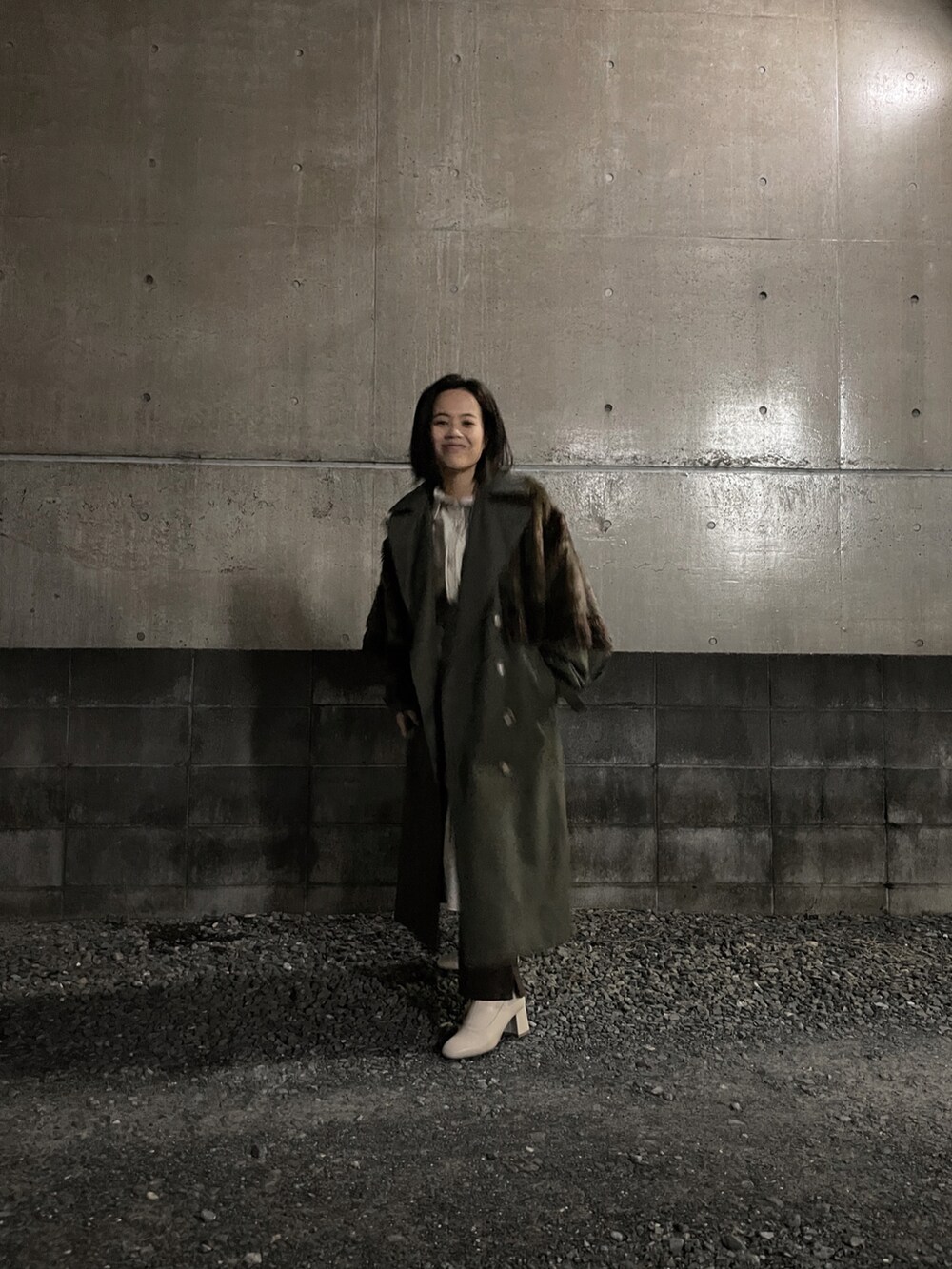 ベージュ系のワンピース、ブラウン系のショルダーバッグ、グリーン系のトレンチコートを着用したレディースの冬コーディネートの2枚目の写真