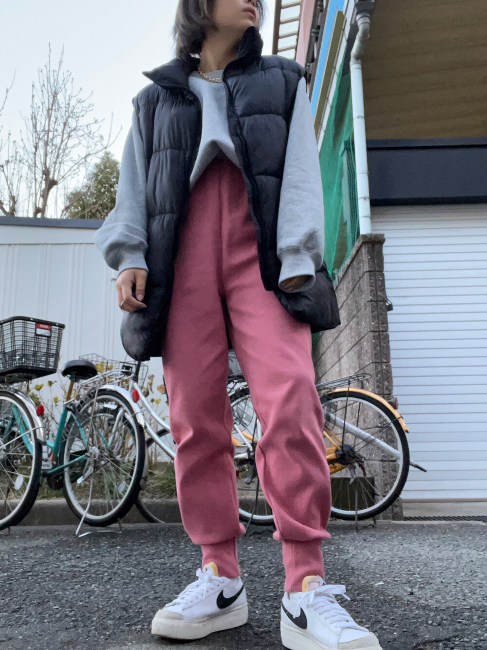 ピンク系のパンツ、グレー系のトップス、ブラック系のダウンベストを着用したレディースの冬コーディネートの2枚目の写真