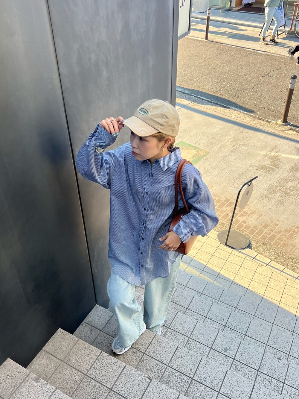 ブルー系のシャツ/ブラウス、ブルー系のデニムパンツ、イエロー系のボストンバッグを着用したレディースの春コーディネートの3枚目の写真