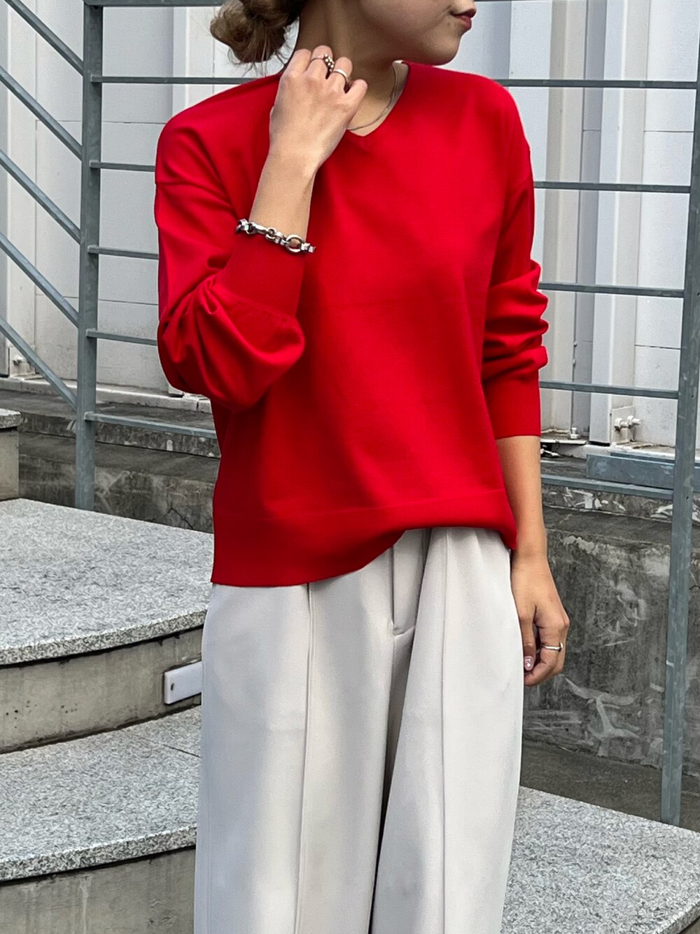 レッド系のニット/セーター、グレー系のスラックス、シルバー系のサンダルを着用したレディースの春コーディネートの4枚目の写真