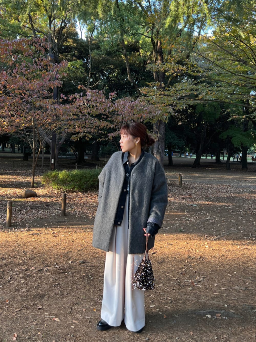 ブラウン系のショルダーバッグ、グレー系のノーカラーコート、ブルー系のデニムジャケットを着用したレディースの秋コーディネートの3枚目の写真