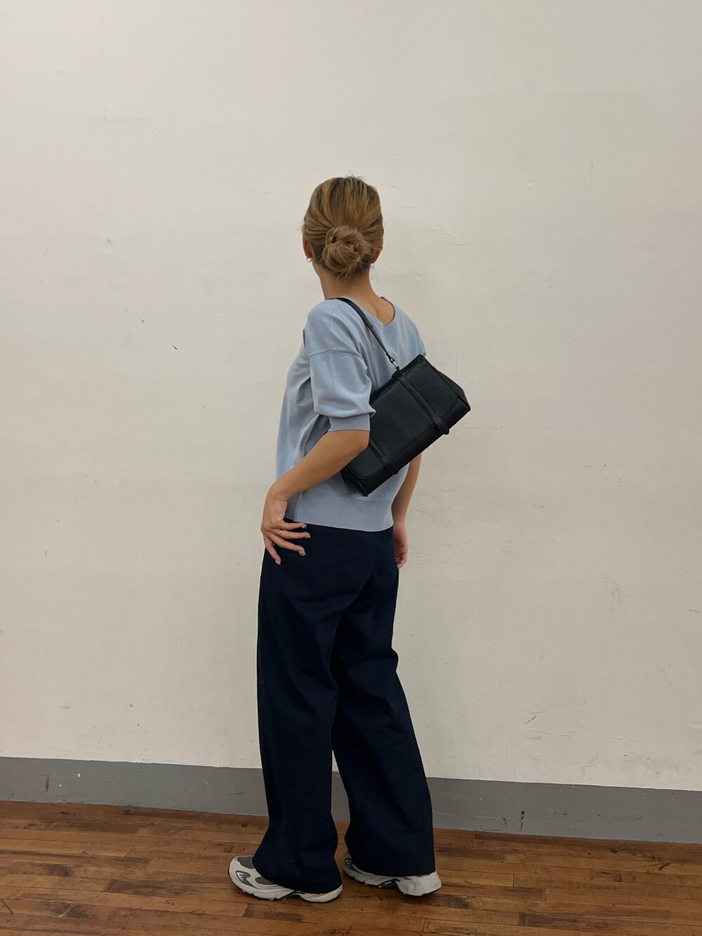 ブルー系のニット/セーター、ブルー系のデニムパンツ、ブラック系のハンドバッグを着用したレディースの春コーディネートの4枚目の写真