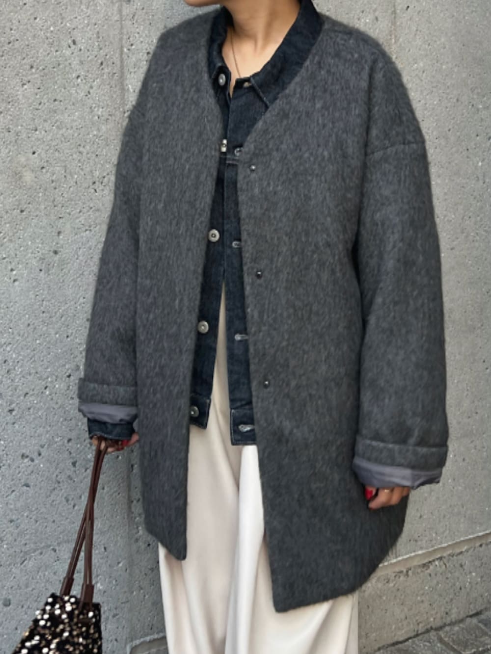 ブラウン系のショルダーバッグ、グレー系のノーカラーコート、ブルー系のデニムジャケットを着用したレディースの秋コーディネートの4枚目の写真