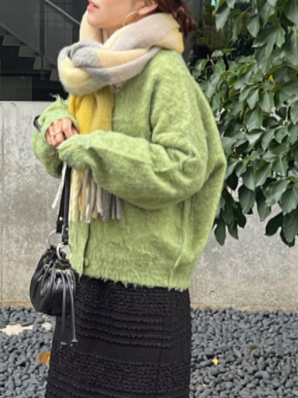 グリーン系のカーディガン/ボレロ、ブラック系のスカート、ブラック系のショルダーバッグを着用したレディースの秋コーディネートの4枚目の写真