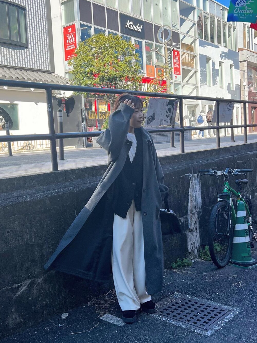 グレー系のステンカラーコート、ホワイト系のその他パンツ、ブラック系のカーディガン/ボレロを着用したレディースの冬コーディネートの2枚目の写真