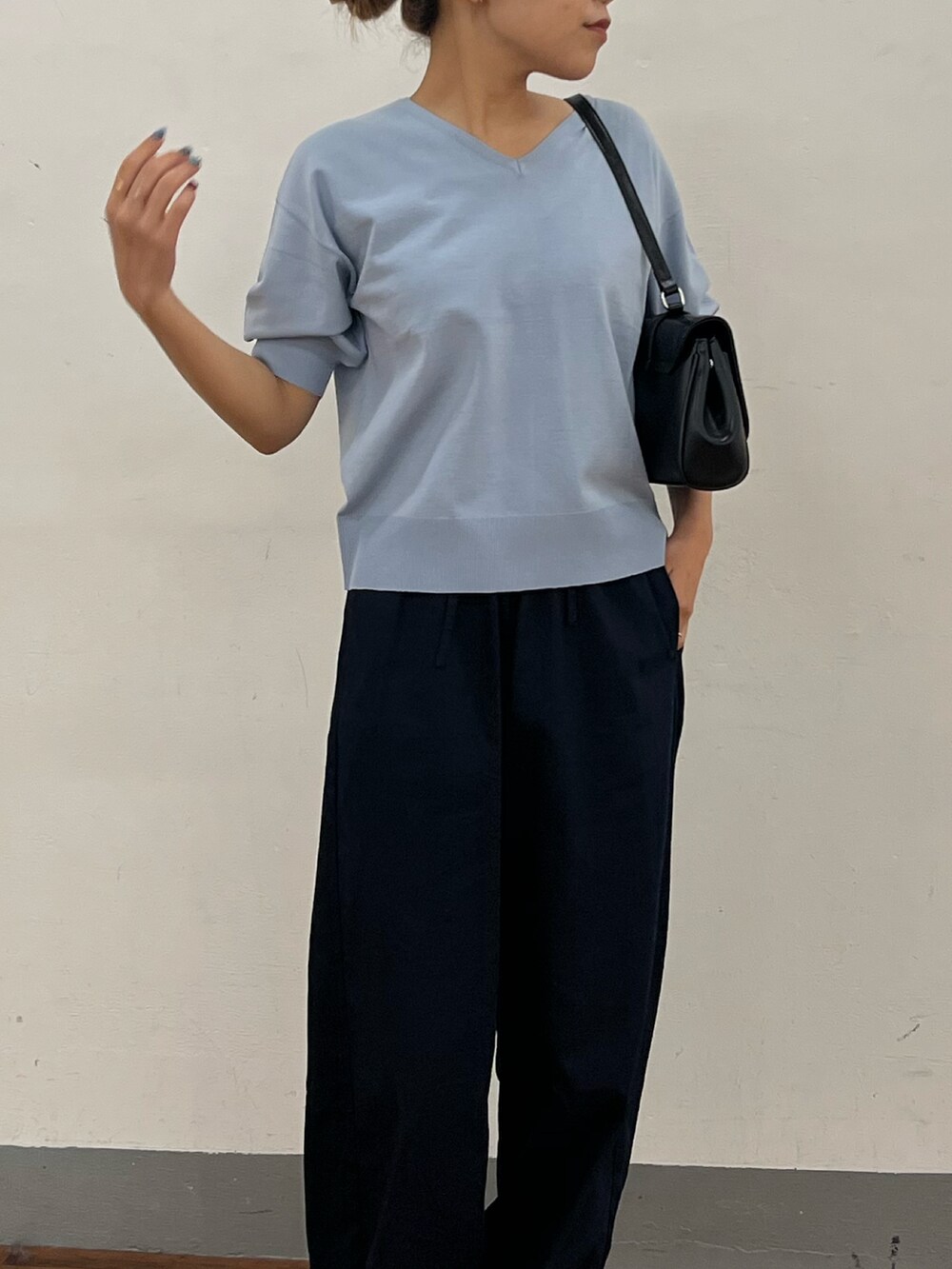 ブルー系のニット/セーター、ブルー系のデニムパンツ、ブラック系のハンドバッグを着用したレディースの春コーディネートの2枚目の写真