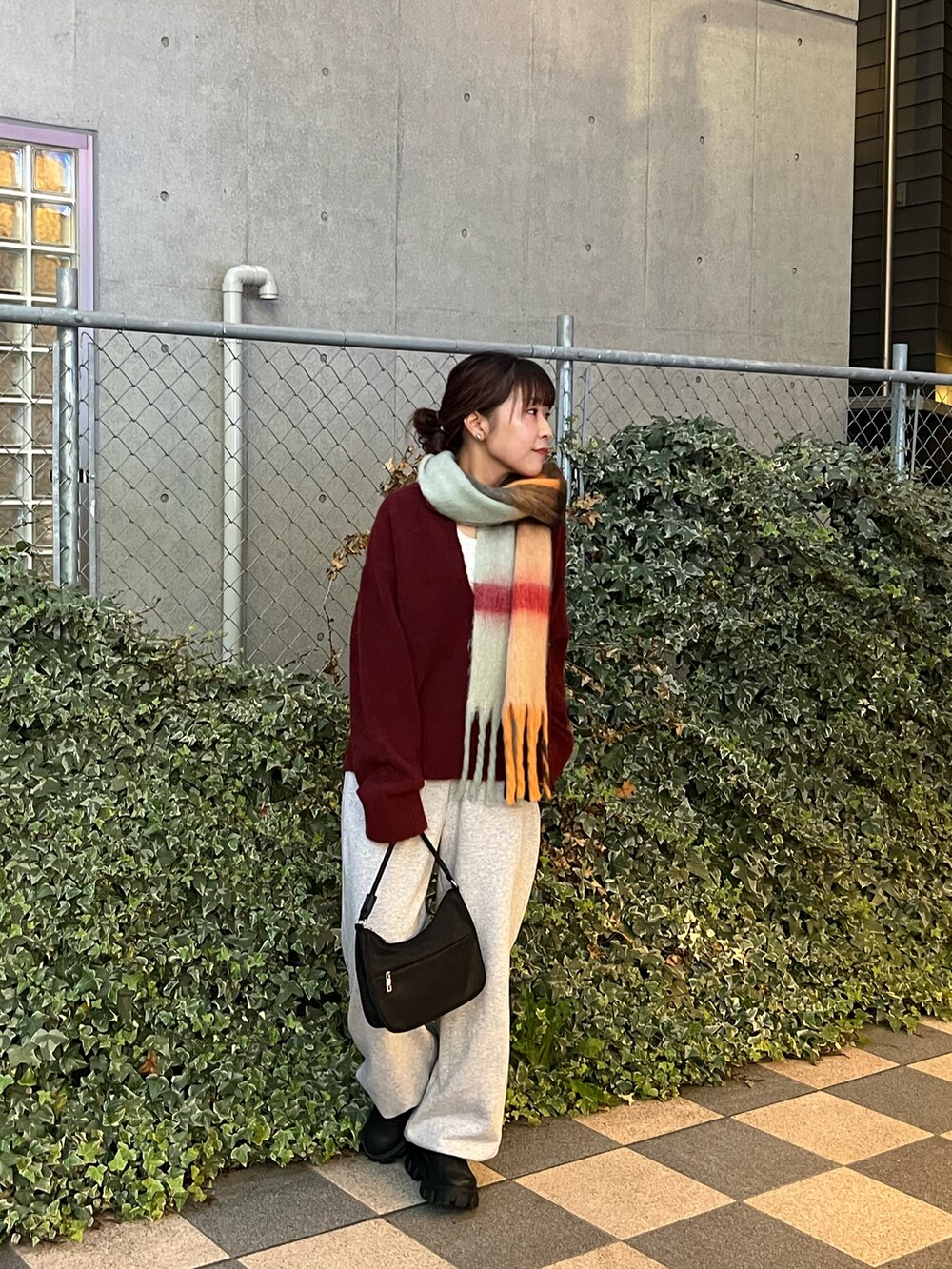 レッド系のニット/セーター、グレー系のスウェットパンツ、ブラック系のハンドバッグを着用したレディースの冬コーディネートの2枚目の写真