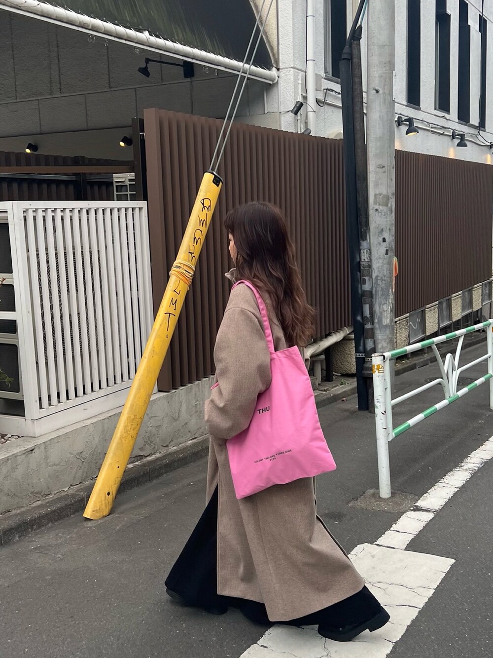 ブラウン系のステンカラーコート、ブラック系のワンピースを着用したレディースの冬コーディネートの2枚目の写真