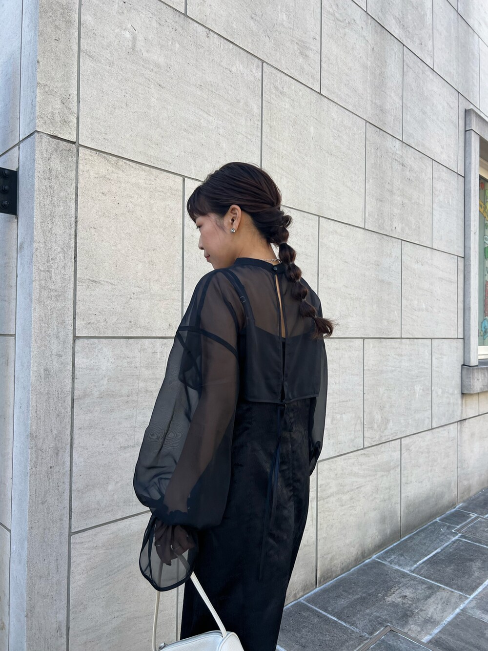 ブラック系のドレス、ホワイト系のハンドバッグ、シルバー系のブーツを着用したレディースの冬コーディネートの2枚目の写真