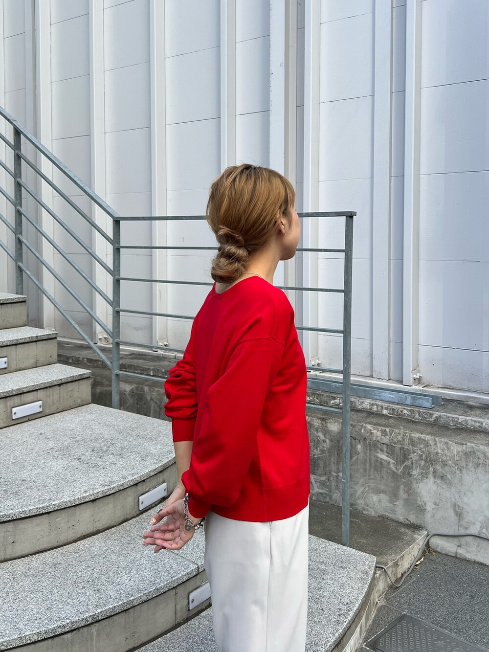 レッド系のニット/セーター、グレー系のスラックス、シルバー系のサンダルを着用したレディースの春コーディネートの3枚目の写真