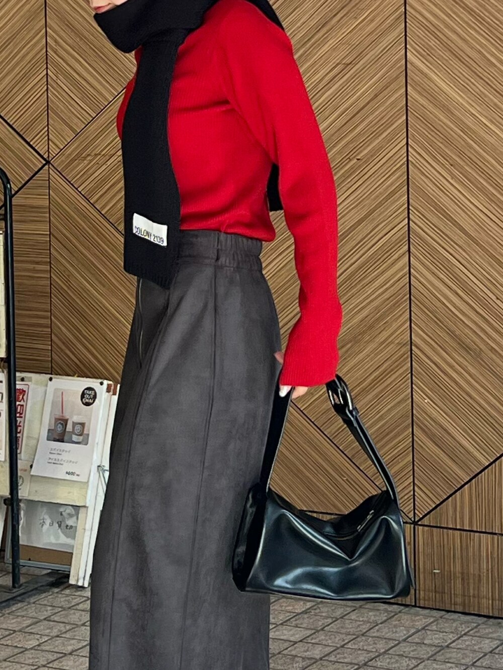 ブラック系のドラムバッグ、レッド系のニット/セーター、ブラック系のスカートを着用したレディースの秋コーディネートの4枚目の写真