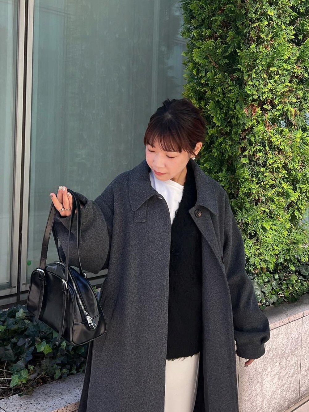 グレー系のステンカラーコート、ホワイト系のその他パンツ、ブラック系のカーディガン/ボレロを着用したレディースの冬コーディネートの3枚目の写真