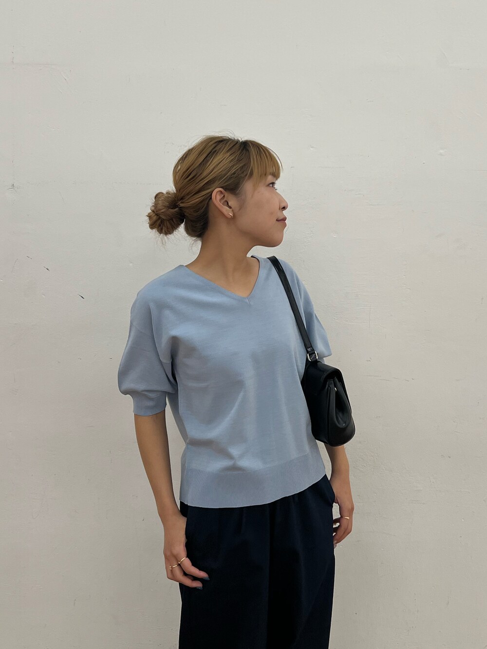 ブルー系のニット/セーター、ブルー系のデニムパンツ、ブラック系のハンドバッグを着用したレディースの春コーディネートの3枚目の写真