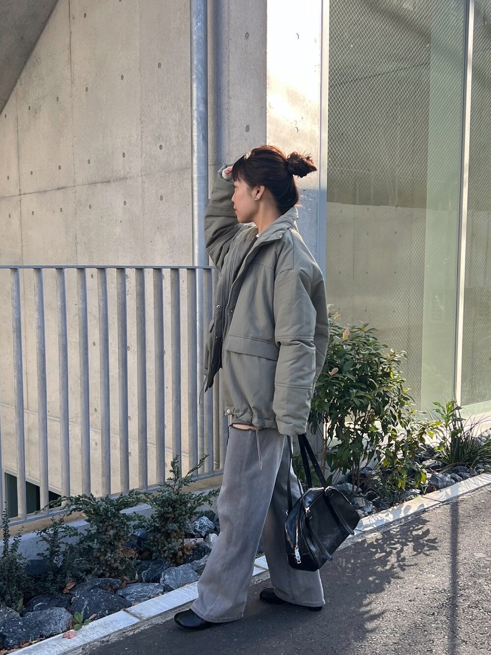 グレー系のデニムパンツ、ブラウン系のニット/セーター、ブラック系のボストンバッグを着用したレディースの冬コーディネートの4枚目の写真