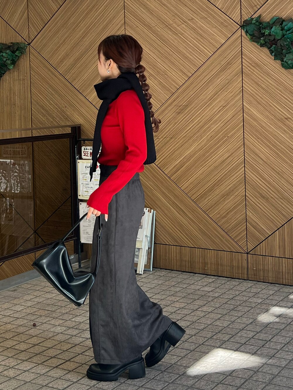 ブラック系のドラムバッグ、レッド系のニット/セーター、ブラック系のスカートを着用したレディースの秋コーディネートの2枚目の写真