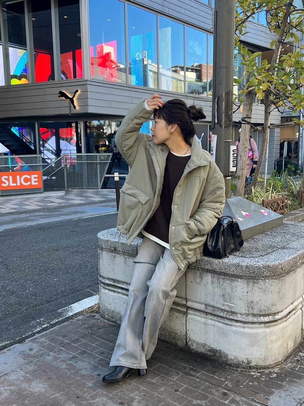 グレー系のデニムパンツ、ブラウン系のニット/セーター、ブラック系のボストンバッグを着用したレディースの冬コーディネートの5枚目の写真