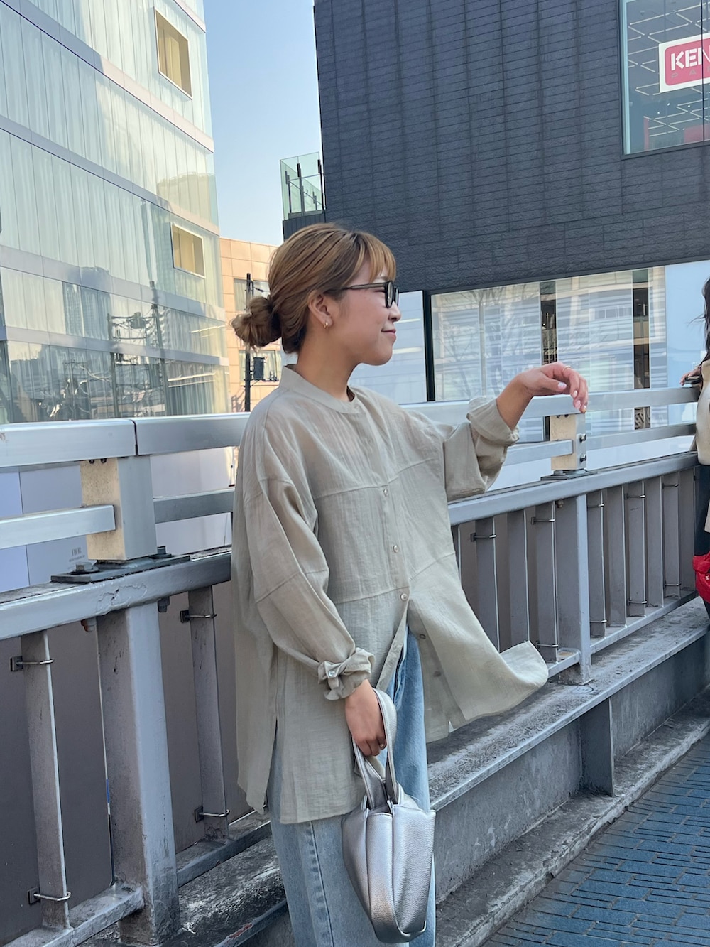 ベージュ系のシャツ/ブラウス、ブルー系のデニムパンツ、シルバー系のハンドバッグを着用したレディースの春コーディネートの2枚目の写真