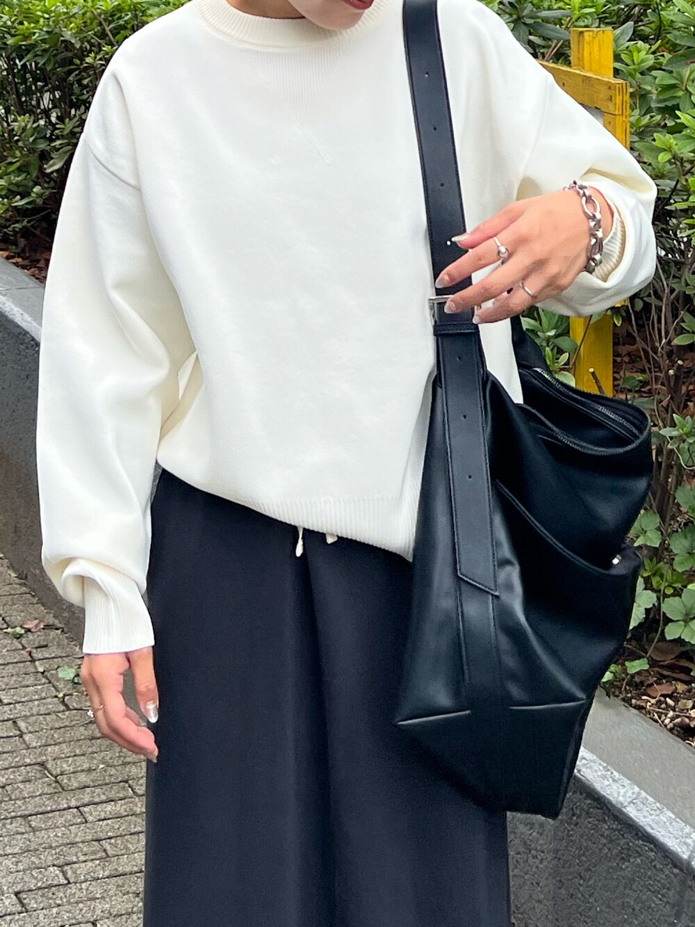 ホワイト系のニット/セーター、ブラック系のスカート、ブラック系のショルダーバッグを着用したレディースの秋コーディネートの3枚目の写真