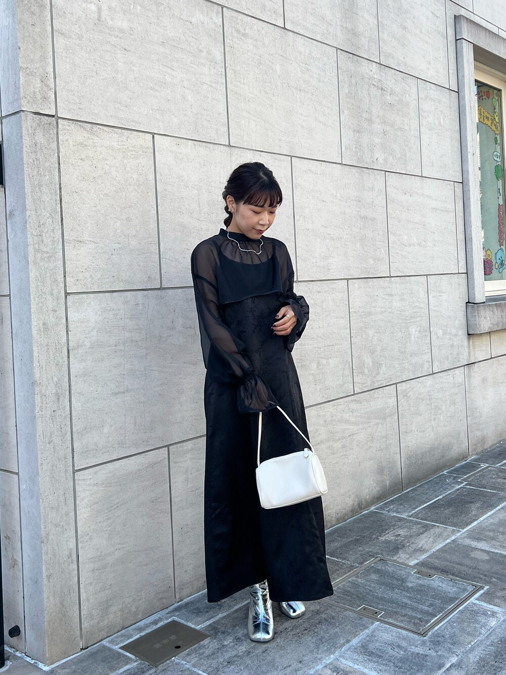 ブラック系のドレス、ホワイト系のハンドバッグ、シルバー系のブーツを着用したレディースの冬コーディネートの4枚目の写真