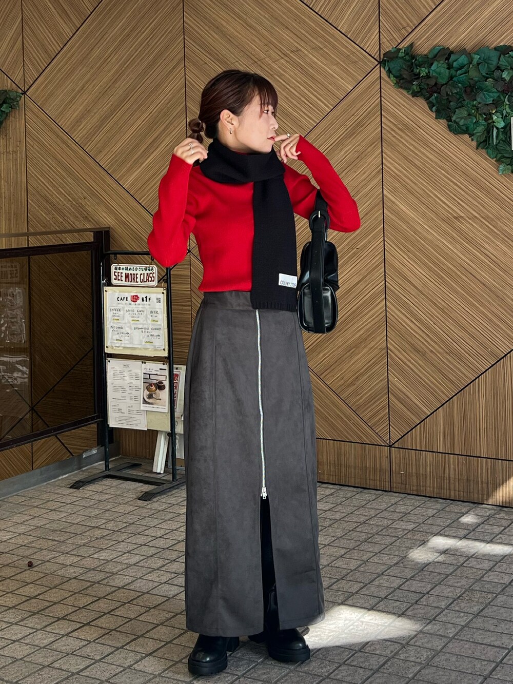 ブラック系のドラムバッグ、レッド系のニット/セーター、ブラック系のスカートを着用したレディースの秋コーディネートの3枚目の写真