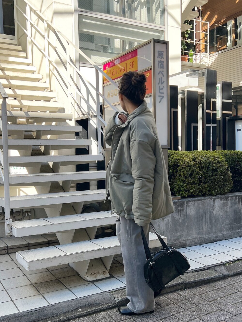 グレー系のデニムパンツ、ブラウン系のニット/セーター、ブラック系のボストンバッグを着用したレディースの冬コーディネートの3枚目の写真