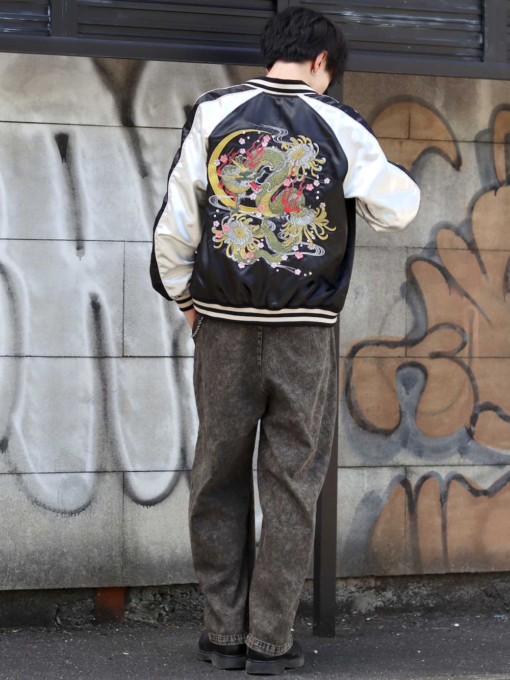 ブラック系のスカジャン、ブラック系のデニムパンツ、ブラック系のドレスシューズを着用したメンズの秋コーディネートの2枚目の写真