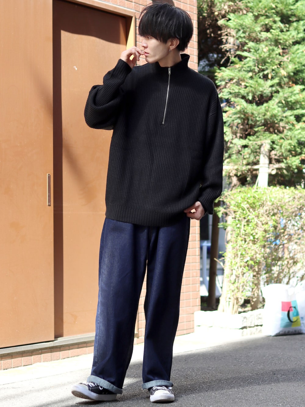 ブラック系のニット/セーター、ブルー系のデニムパンツ、ブラック系のスニーカーを着用したメンズの秋コーディネートの2枚目の写真