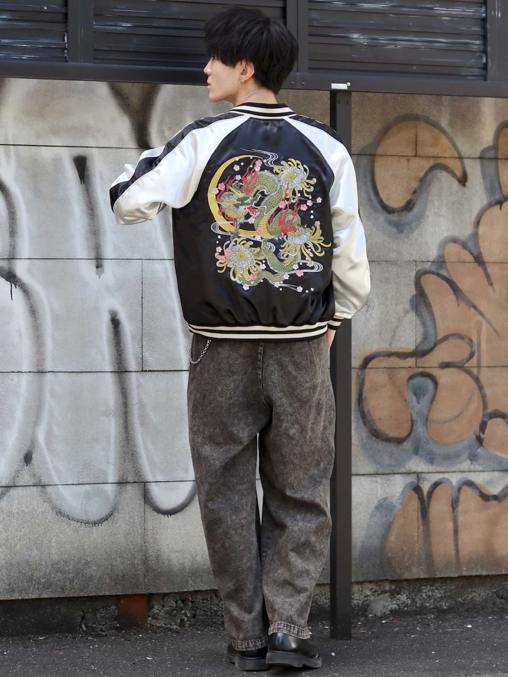 ブラック系のスカジャン、ブラック系のデニムパンツ、ブラック系のドレスシューズを着用したメンズの秋コーディネートの3枚目の写真