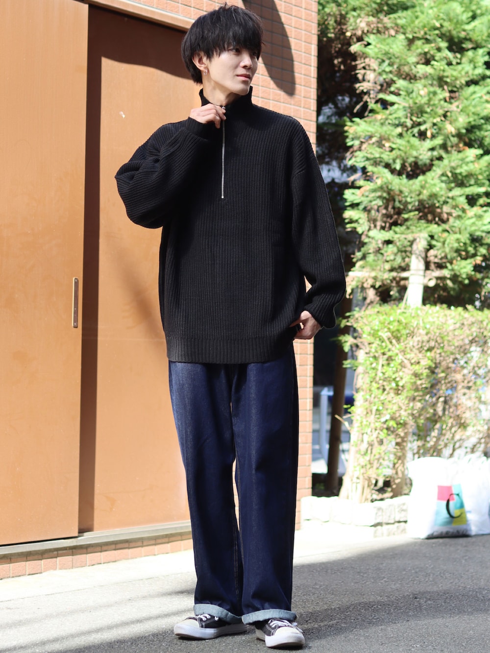 ブラック系のニット/セーター、ブルー系のデニムパンツ、ブラック系のスニーカーを着用したメンズの秋コーディネートの4枚目の写真