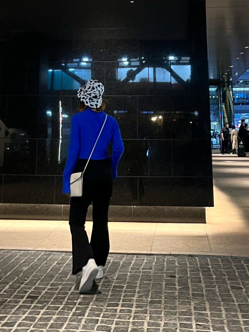 ホワイト系のスニーカー、ブラウン系のベルトを着用したレディースの秋コーディネートの2枚目の写真