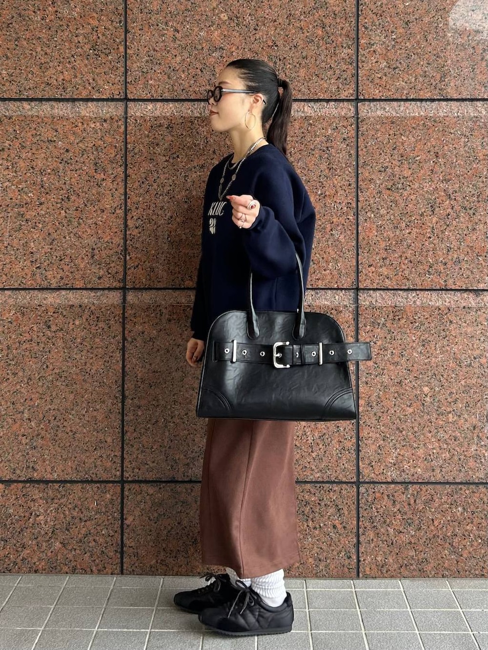 ブラウン系のスカート、ブラック系のショルダーバッグ、ブラック系のスニーカーを着用したレディースの秋コーディネートの2枚目の写真