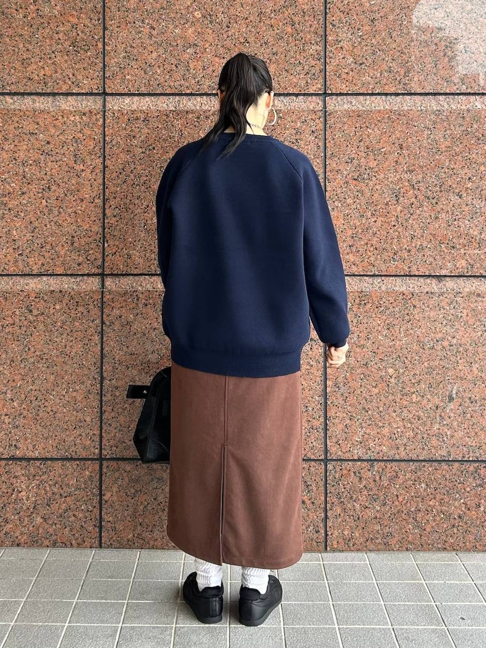 ブラウン系のスカート、ブラック系のショルダーバッグ、ブラック系のスニーカーを着用したレディースの秋コーディネートの3枚目の写真