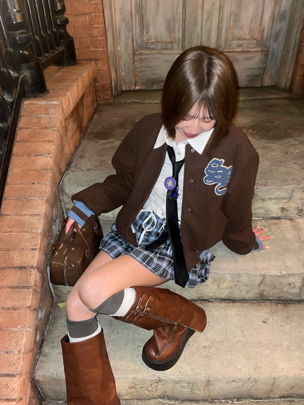 ブラウン系のボストンバッグ、ブラウン系のスタジャン、ブルー系のスカートを着用したレディースの冬コーディネートの4枚目の写真