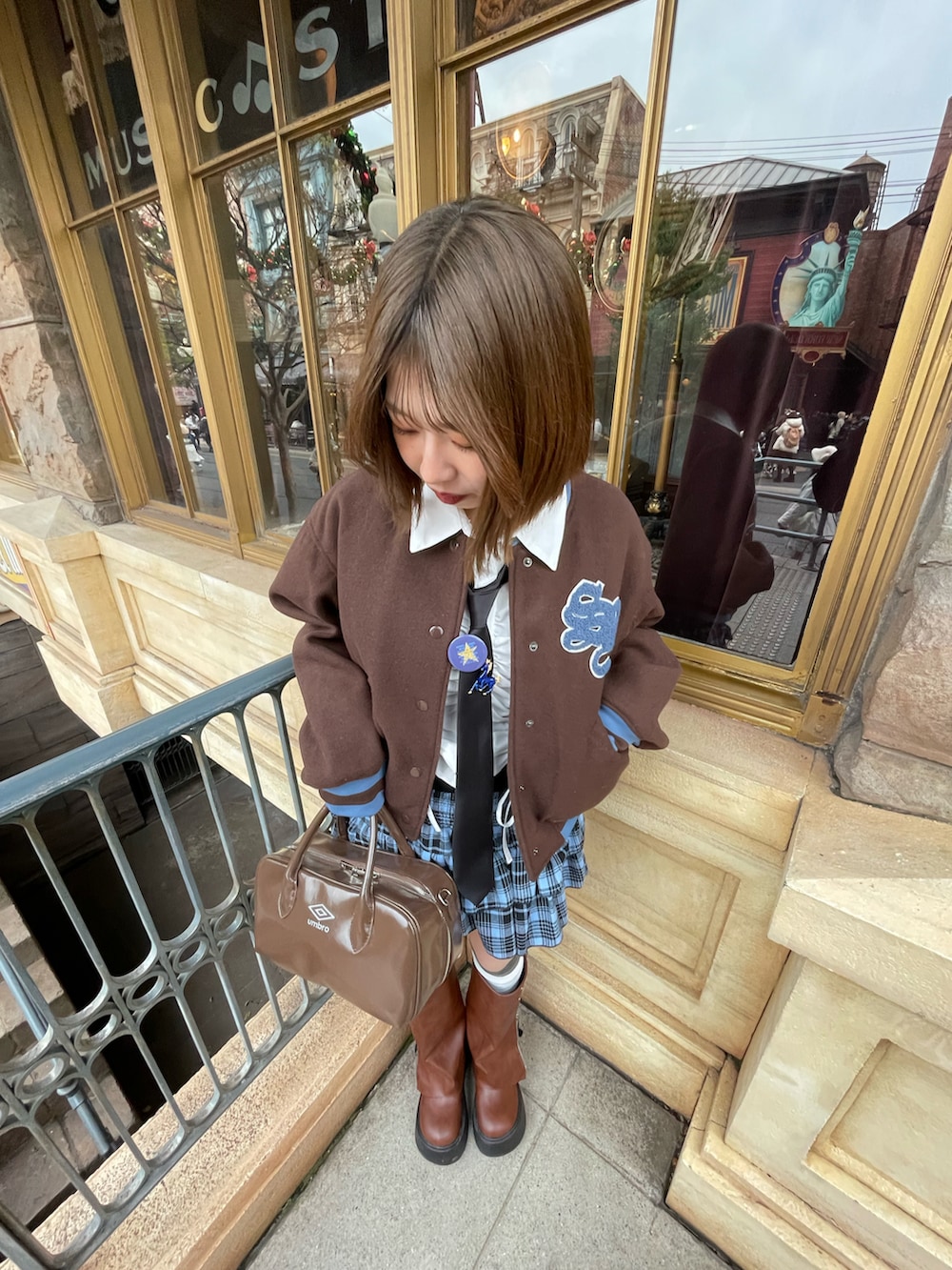 ブラウン系のボストンバッグ、ブラウン系のスタジャン、ブルー系のスカートを着用したレディースの冬コーディネートの2枚目の写真