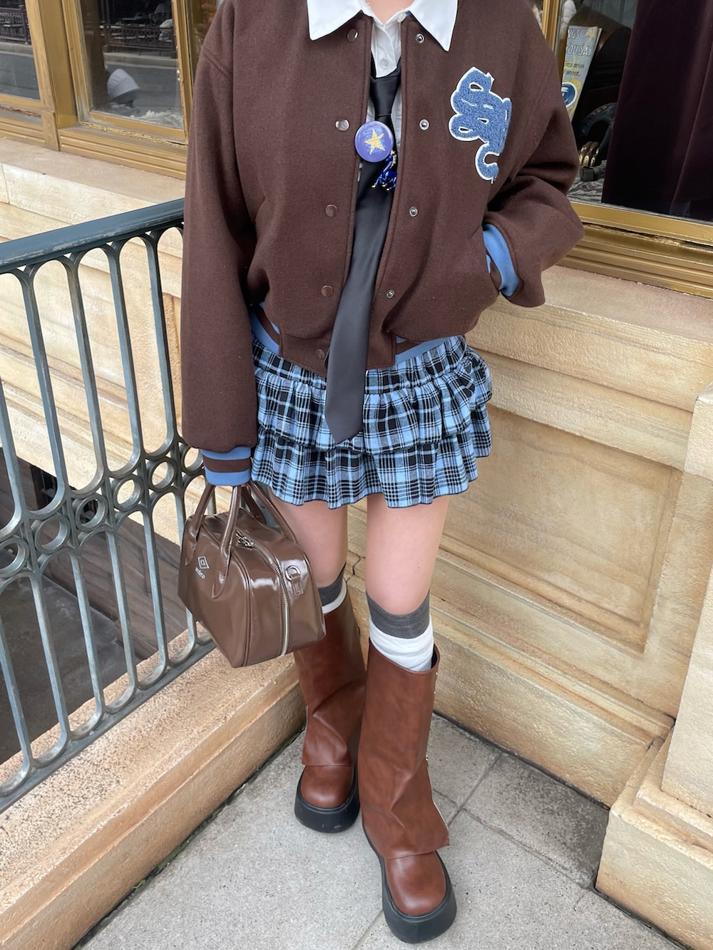 ブラウン系のボストンバッグ、ブラウン系のスタジャン、ブルー系のスカートを着用したレディースの冬コーディネートの3枚目の写真