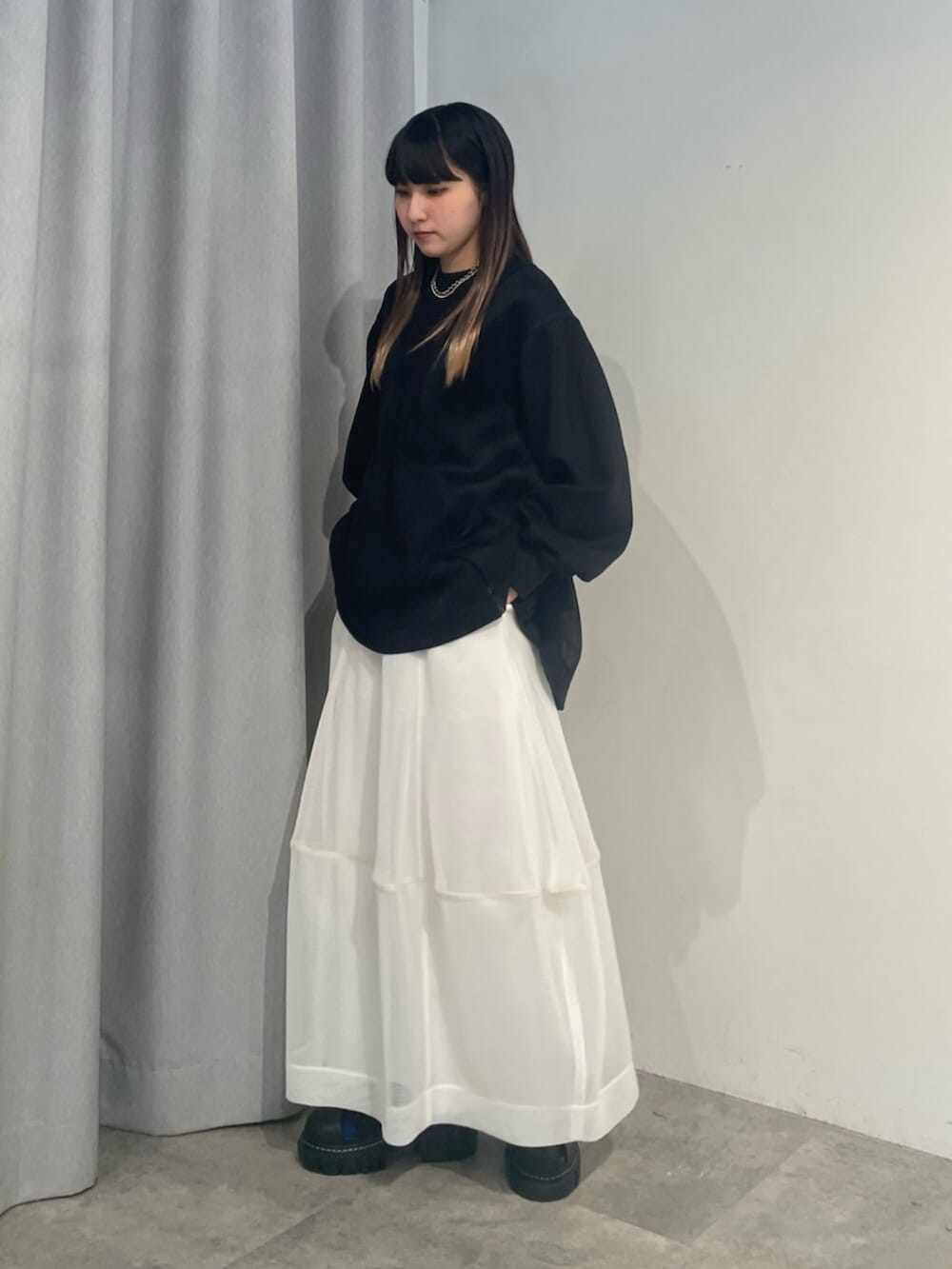 ブラック系のTシャツ/カットソー、ホワイト系のスカート、ブラック系のサンダルを着用したレディースの冬コーディネートの2枚目の写真