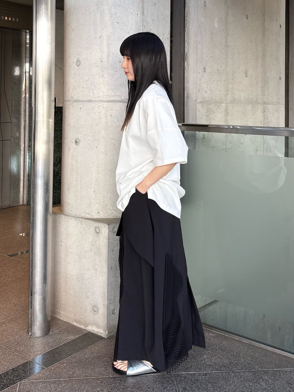 シルバー系のサンダル、ホワイト系のTシャツ/カットソー、ブラック系のスカートを着用したレディースの春コーディネートの2枚目の写真